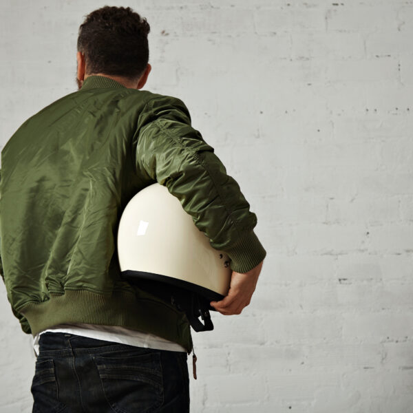 Back portrait man jeans khaki short jacket with sparkling white motorcycle helmet his arm isolated white 600x600
